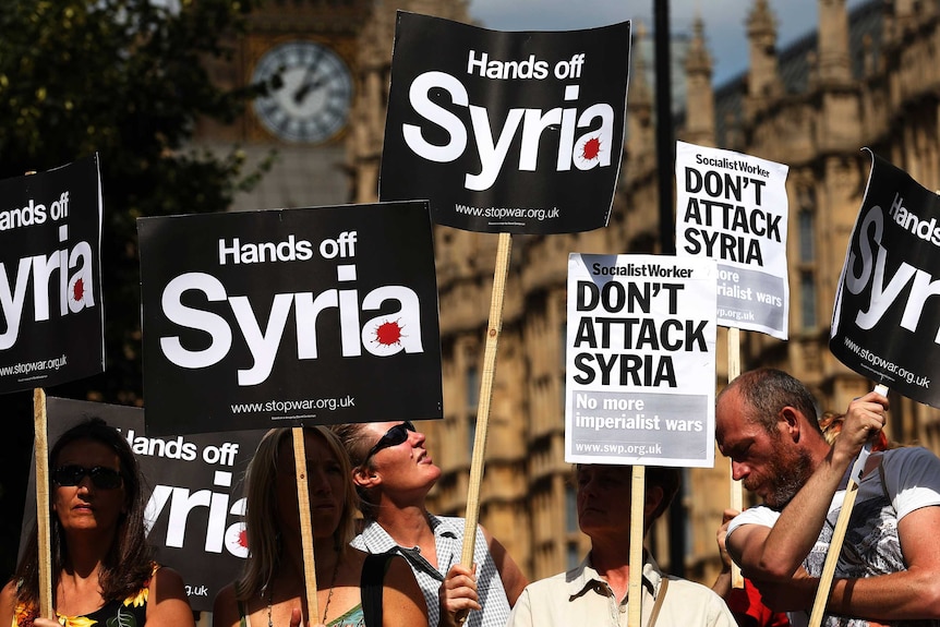 Demonstrators hold placards outside the Houses of Parliament in London