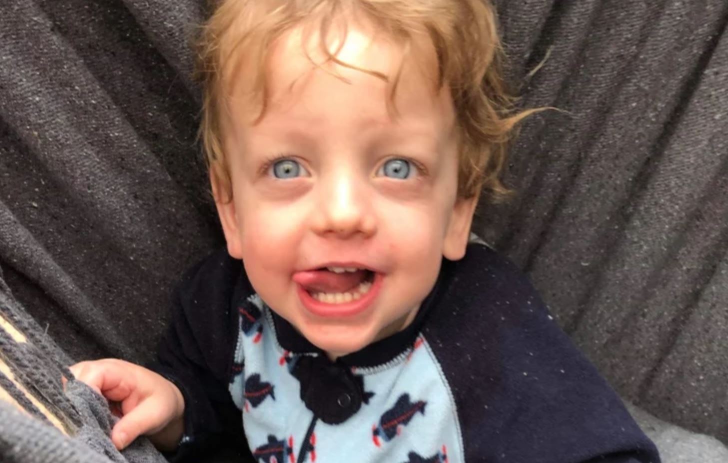 A photo of a toddle with blonde hair and blue eyes looking into the camera.