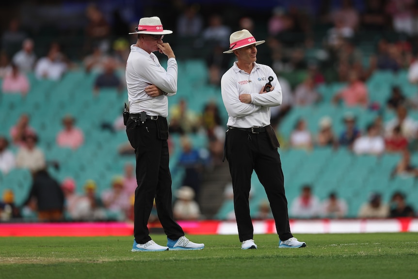 Umpires Paul Reiffel and Chris Gaffaney stand on the SCG pitch while holding a light meter during a Test.
