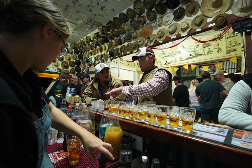 Men lining up drinks on pub bar