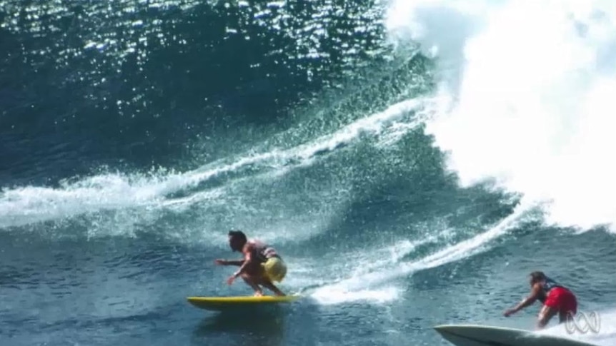 A pair of surfers take on a large wave in Hawaii in the 1970s