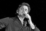Black and white image of Johnny Cash performing onstage.