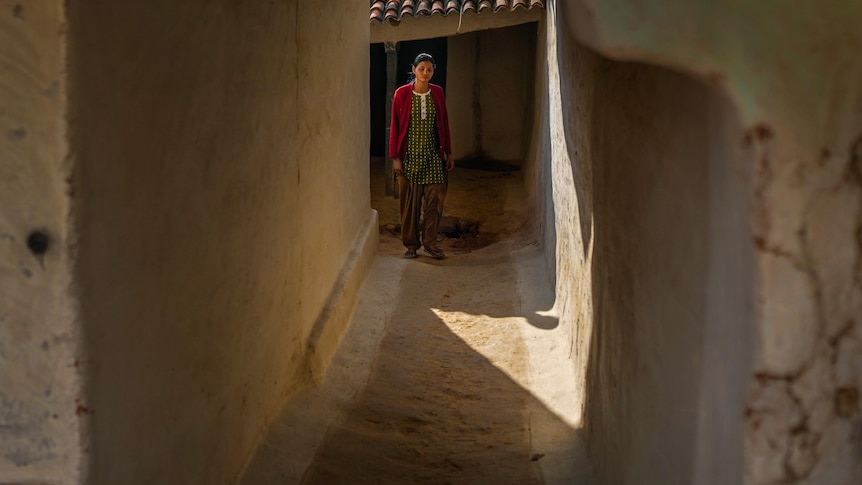 A woman stands outside her house in a village in Ambikapur, India