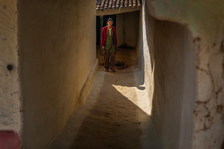 A woman stands outside her house in a village in Ambikapur, India