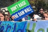 Children hold a sign which reads 'World Heritage' while someone behind them holds a sign saying 'Don't Raise the Dam Wall'