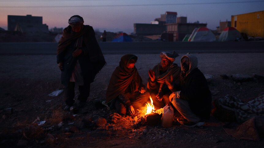 Men from Ghor province warm themselves by fires and in makeshift shelters and tents.