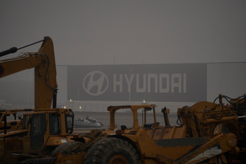 construction equipment in the foreground as a hyundai signed can be seen at a factory