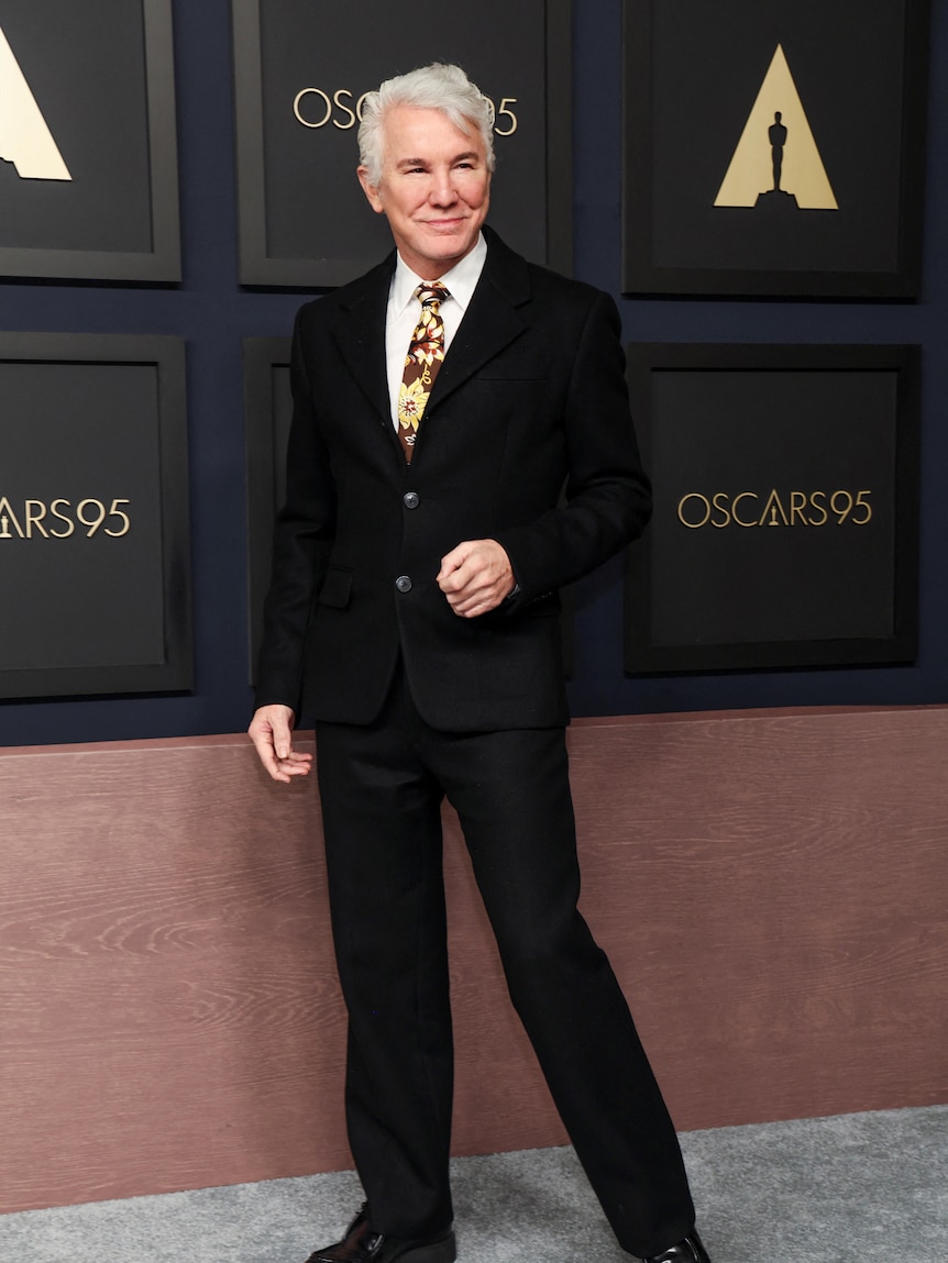 Baz Luhrman stands on the Oscars red carpet. 