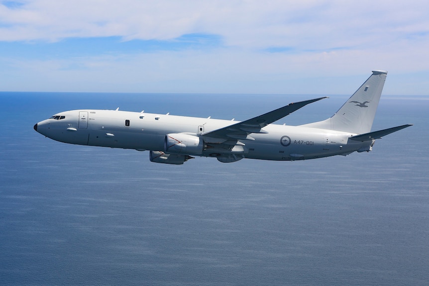 A side view of a P-8A Poseidon showing it fly above an ocean at day time 