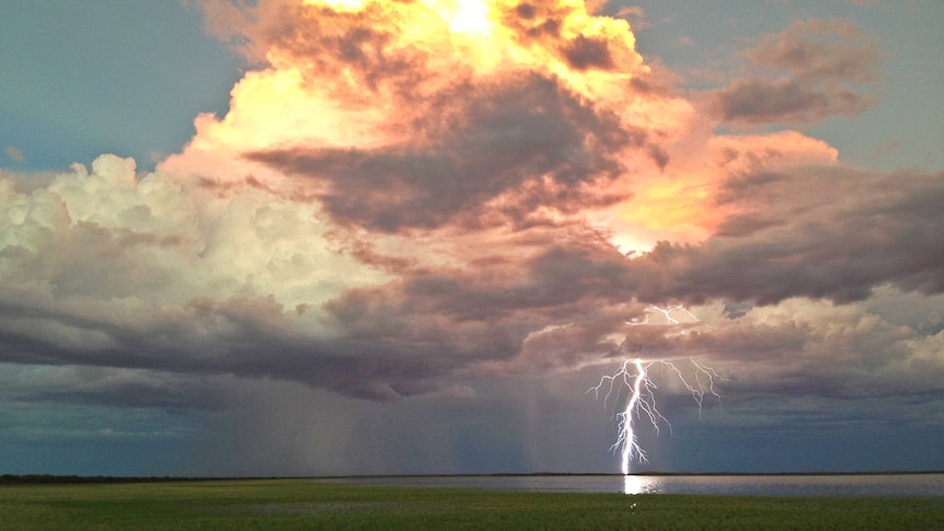 Huge thunder cloud and giant bolt of lightning over a lake