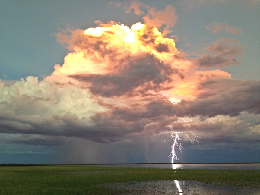 Huge thunder cloud and giant bolt of lightning over a lake