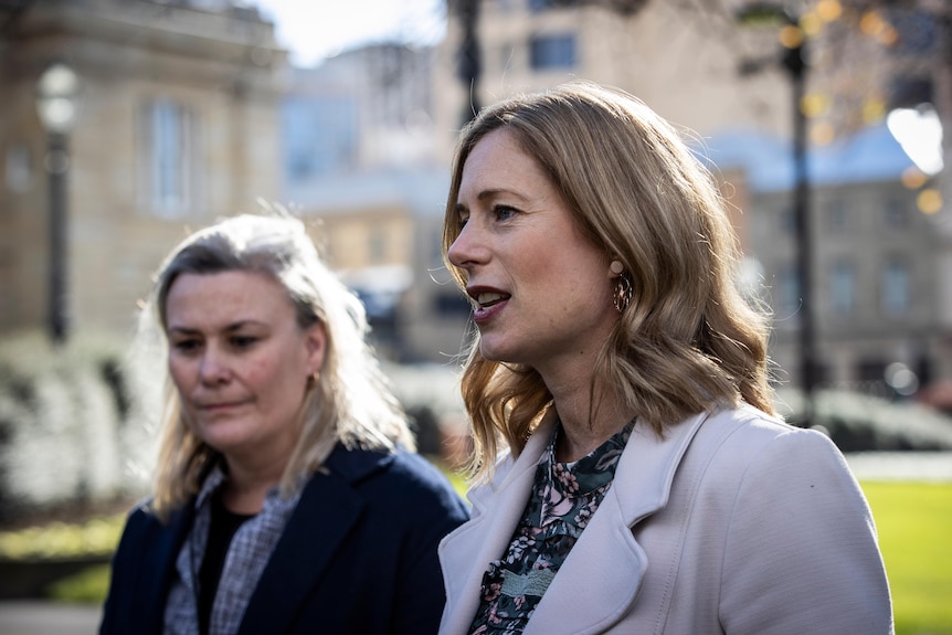 A blonde woman, formally dressed, stands outside addressing the media.