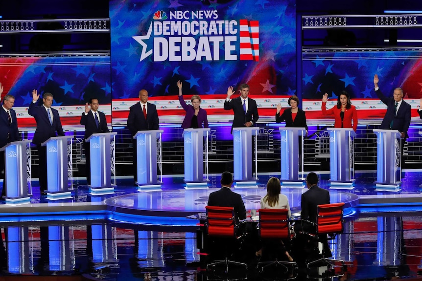 Ten people at individual lecterns with their arms raised