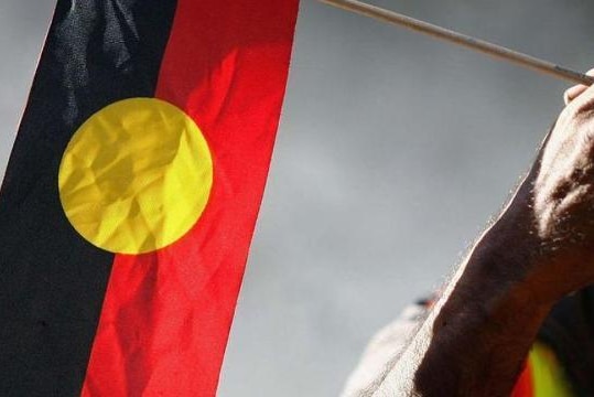 Hand holds small Aboriginal flag