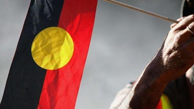 Hand holds small Aboriginal flag