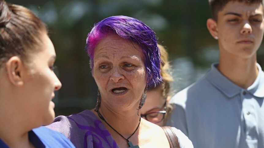 Varri Telfer speaks to media outside court while surrounded by family.