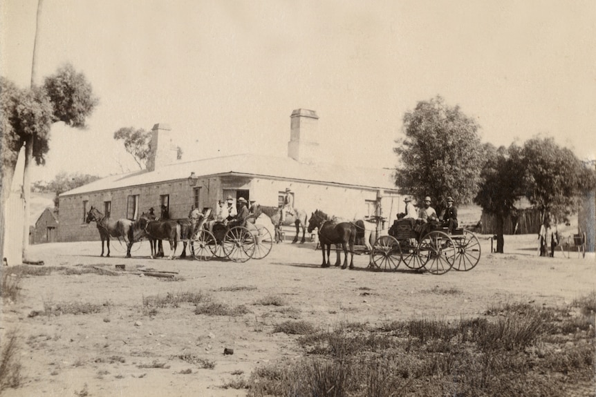 An old photo of horse and carriages outside a building