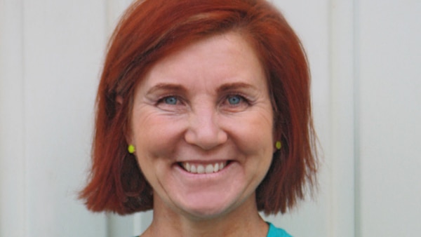 A portrait of a smiling woman with short red hair.