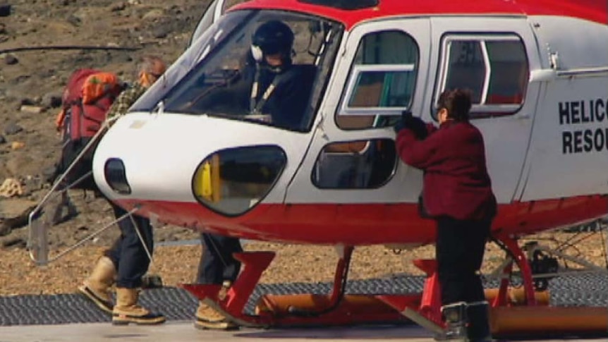 A pilot sits in a Squirrel helicopter as passengers board in Antarctica.