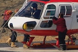 A pilot sits in a Squirrel helicopter as passengers board in Antarctica.