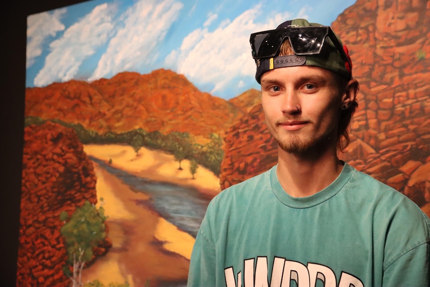 A student stands in front of his painting.