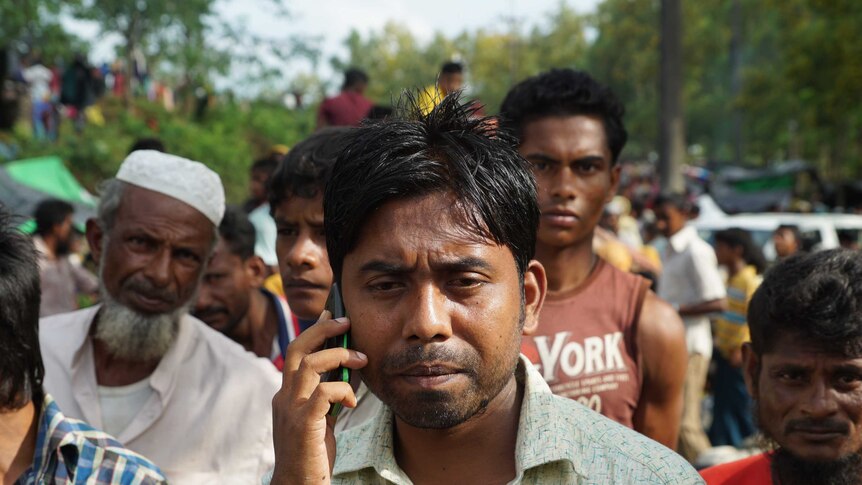Noor Mohammad on a mobile phone amidst a crowd at Kutupalong camp in Bangladesh.