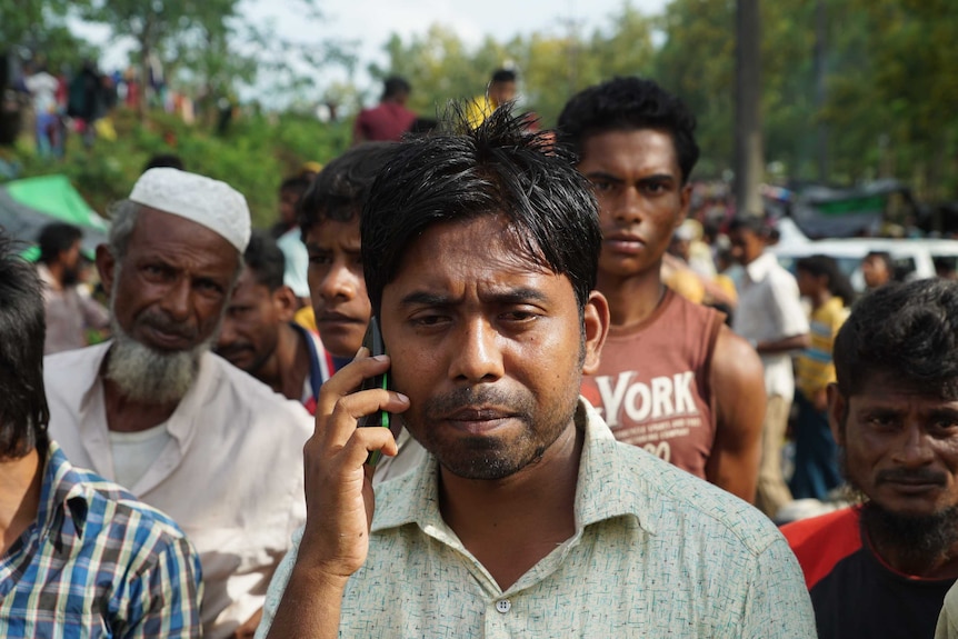 Noor Mohammad on a mobile phone amidst a crowd at Kutupalong camp in Bangladesh.