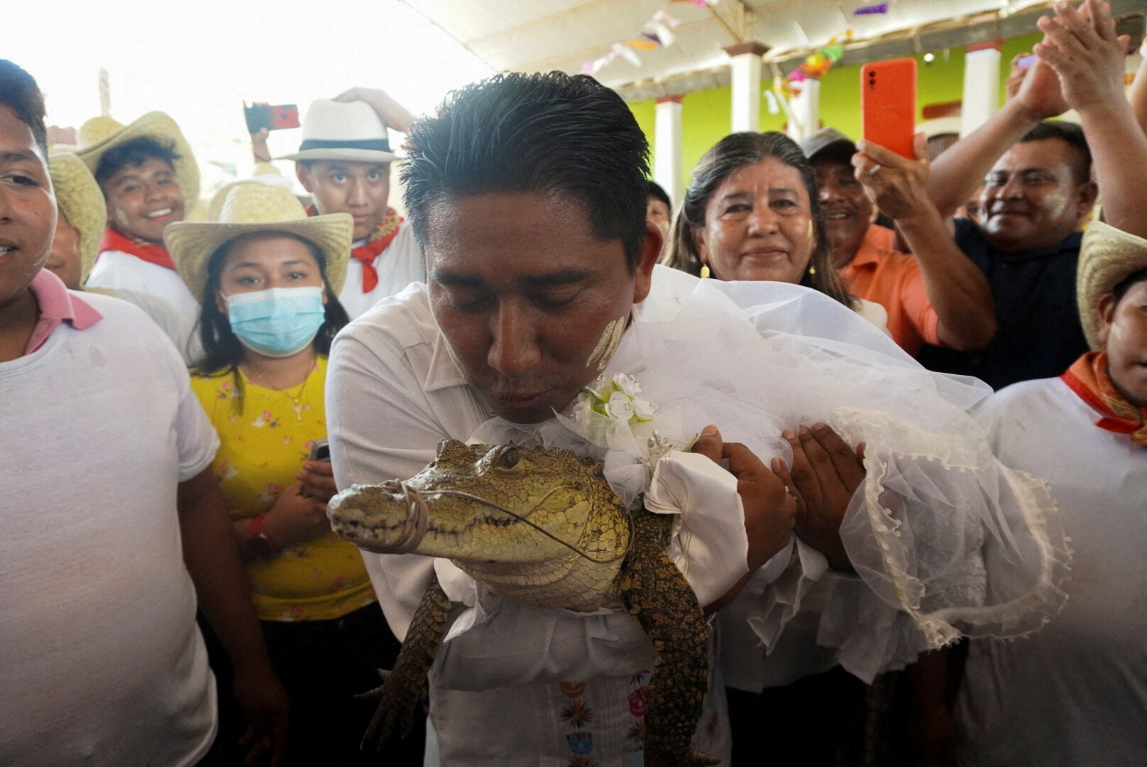 Mexican mayor seen kissing an alligator dressed as a bride during a traditional ritual marriage.