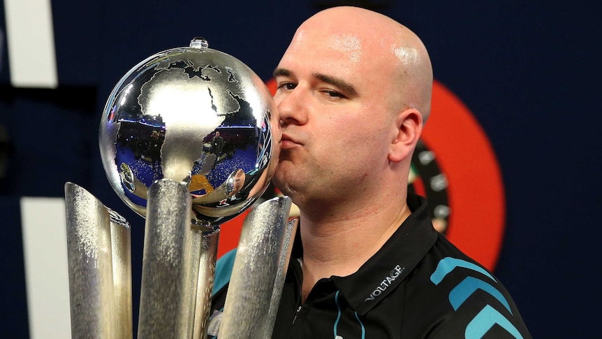 Britain's Rob Cross kisses the trophy after winning world darts championship final over Phil Taylor.