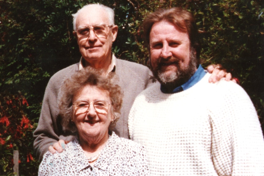 A photo from the 90s of a young man with his two older parents