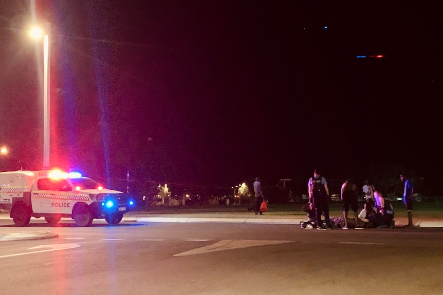 Police officers gather on a dark street in Broome