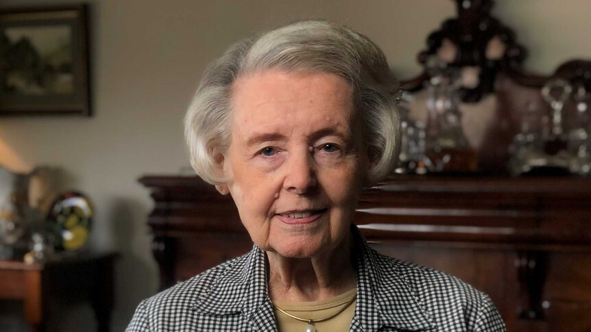 An elderly woman in a dark lounge room