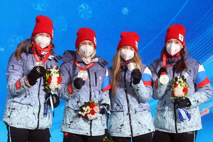 Les athlètes féminines russes se tiennent sur un podium brandissant des médailles d'argent