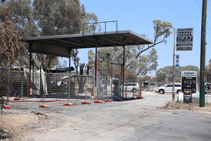 A burnt out petrol station with cyclone fencing around it.