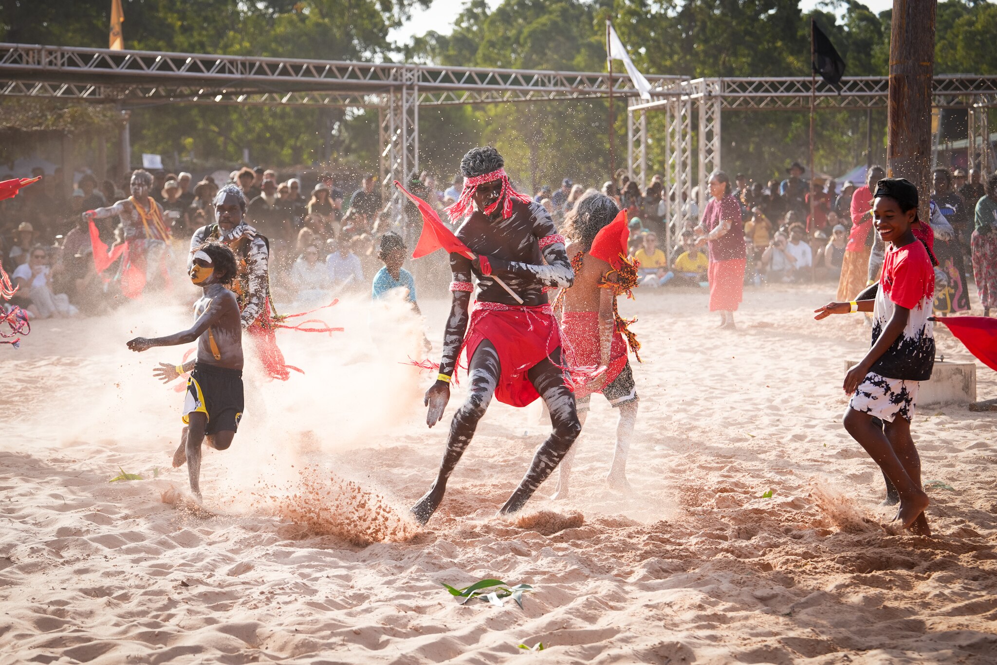 A group of dancers in red throw up sand with their feet