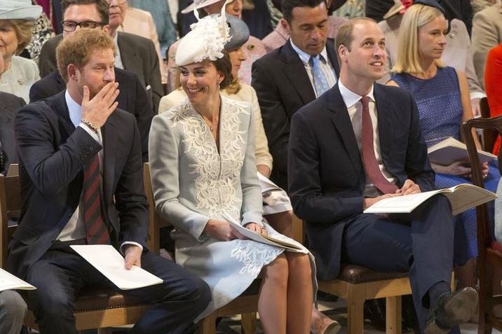 Kate Middleton sits in between Prince Harry and Prince William, smiling at Harry