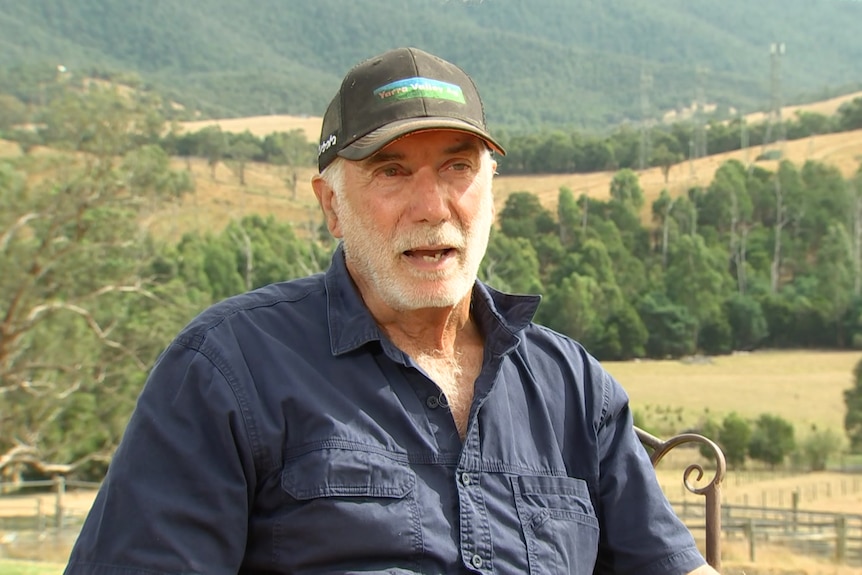 A man in a baseball cap with a mountain in the background.