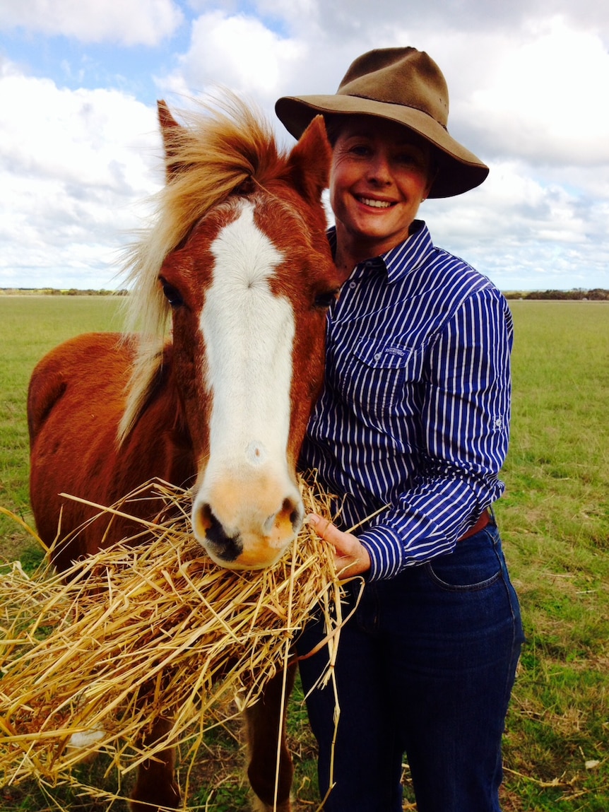 Gemma Walker holds a handful of hay out to Dash the pony who is munching away