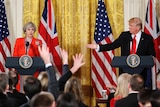 Reporters raise their hands as Donald Trump gestures to Theresa May in a White House press conference.