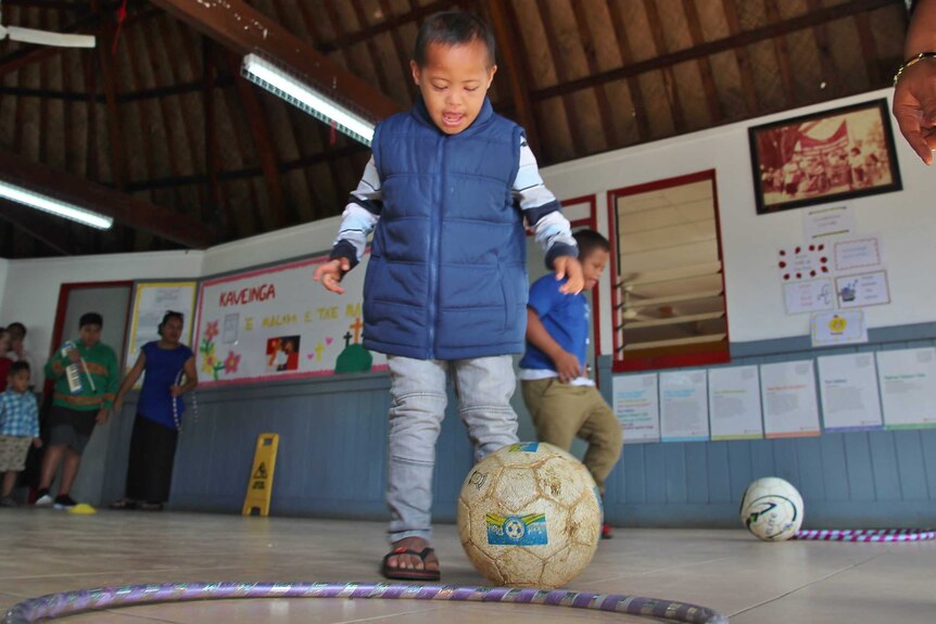 A young boy stands with a soccer ball at his feet.
