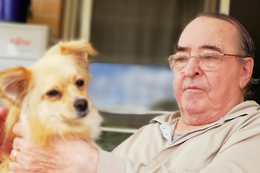 Trevor Moir holding a small red dog.