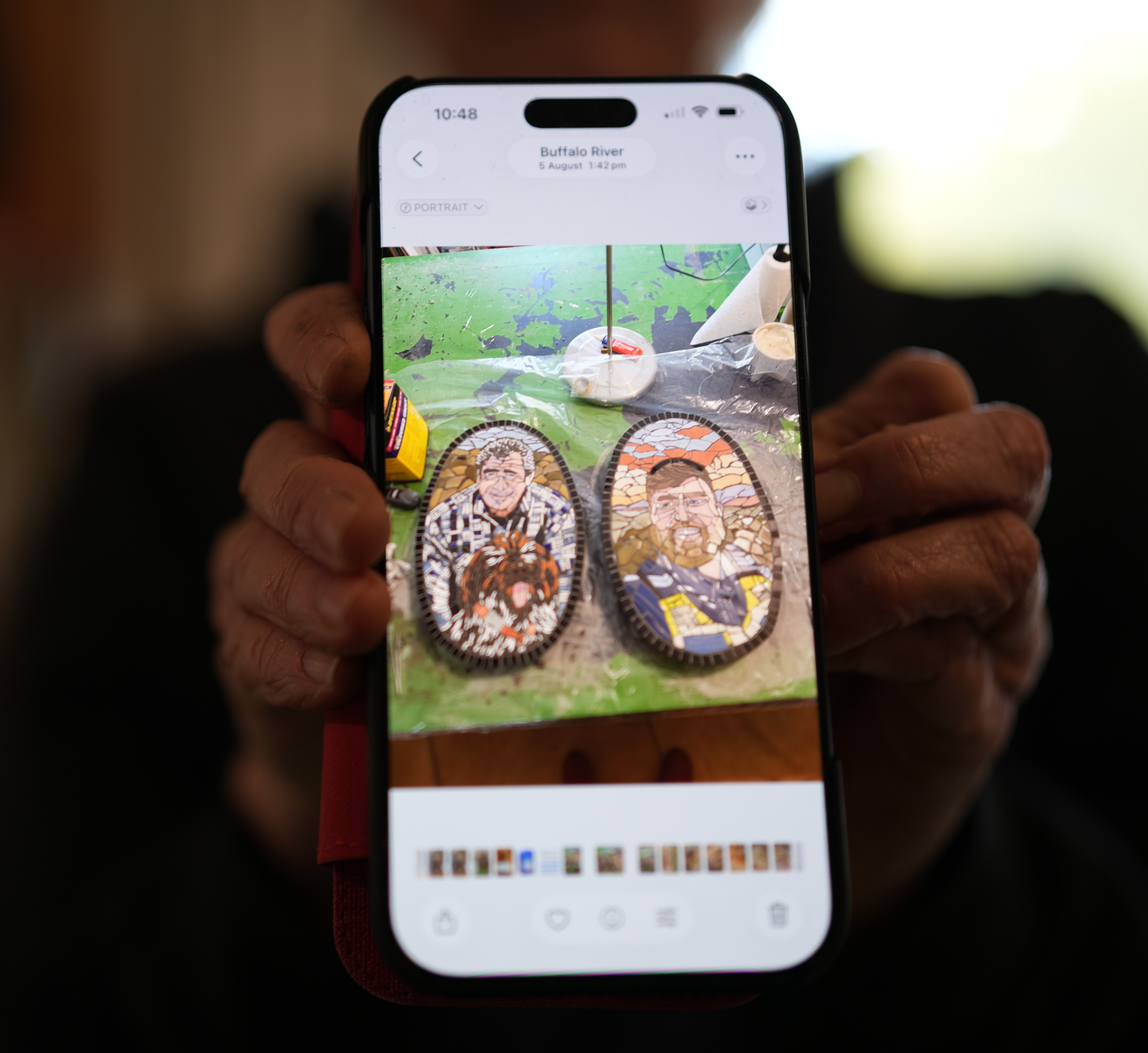 A woman holding a phone in her hands with a picture of mosaic artwork.