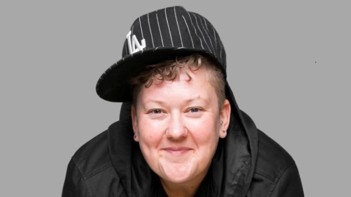 Kirsty wears a baseball cap and black jacket as she smiles at the camera