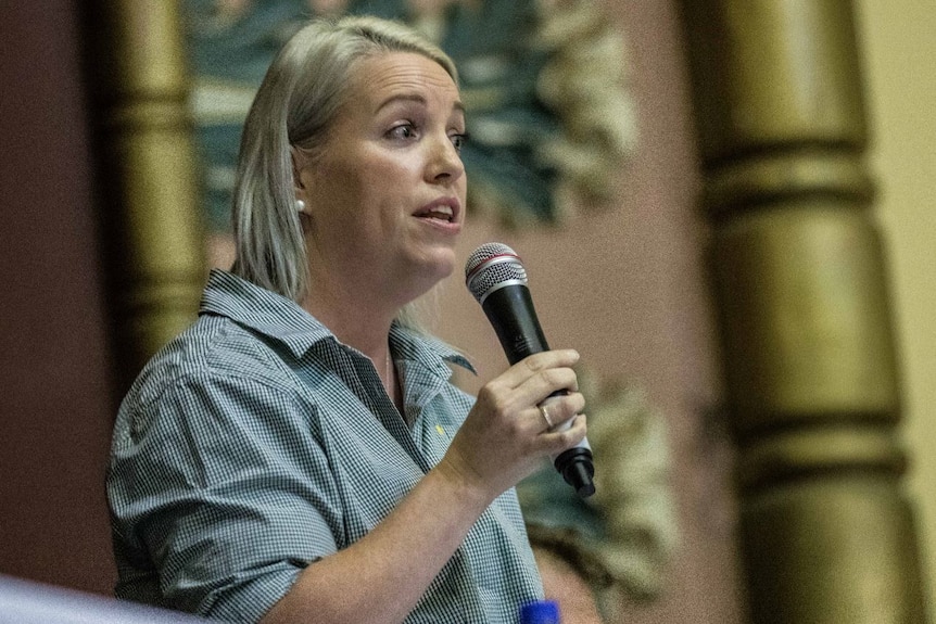 A woman in a green shirt, speaking into a microphone.