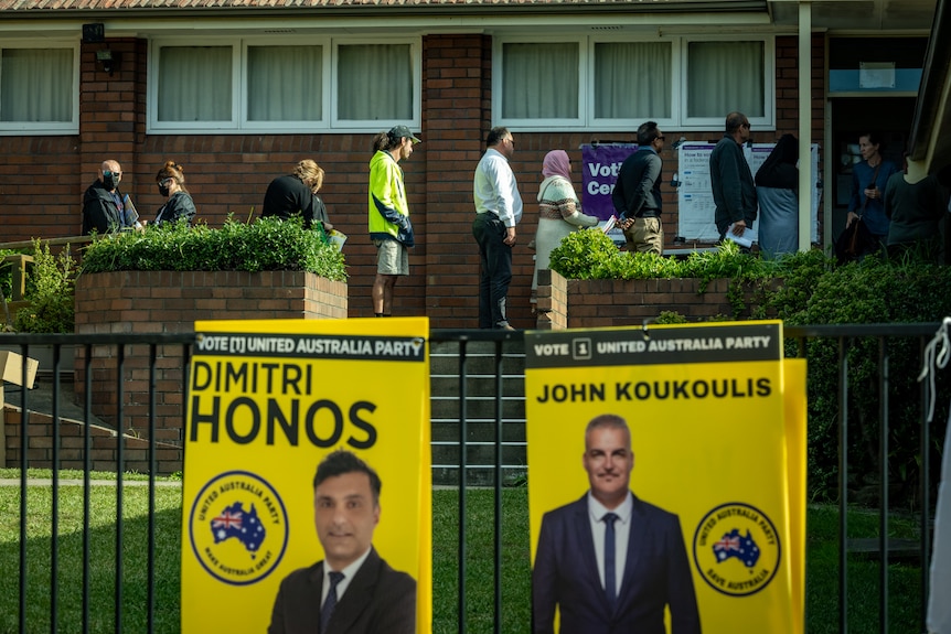 Bright yellow posters featuring two UAP candidates are attached to a fence outside an early voting centre.