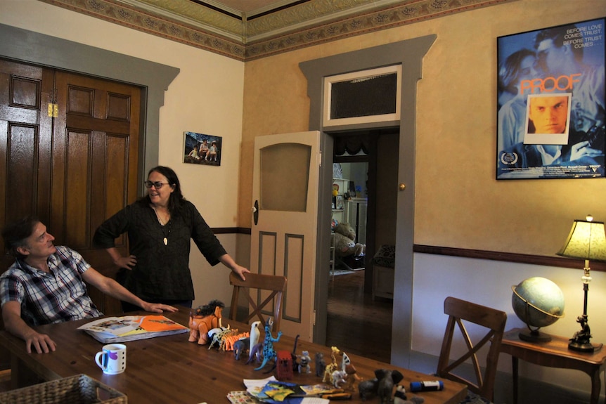 A man seated and a woman standing in a dining room