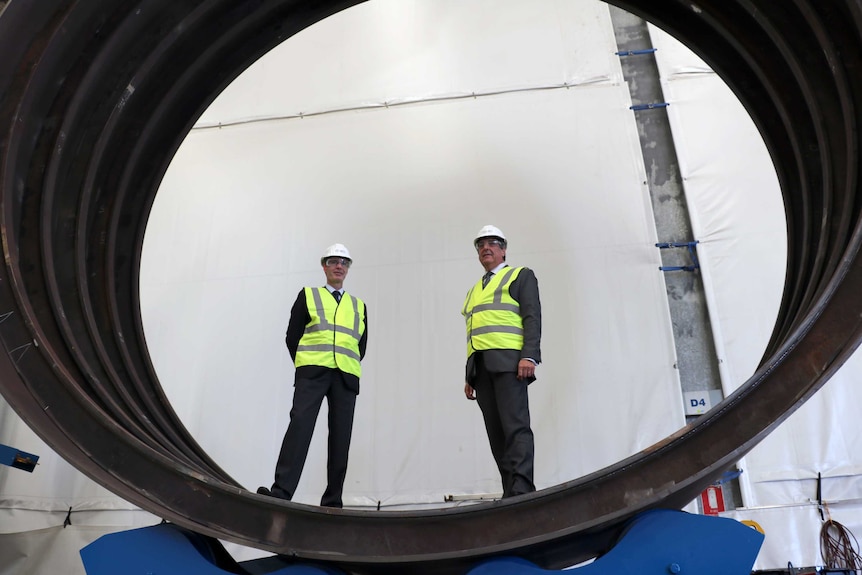 Philip Stanford from ThyssenKrupp and Mike Deeks from CIVMEC stand behind the submarine hull part.