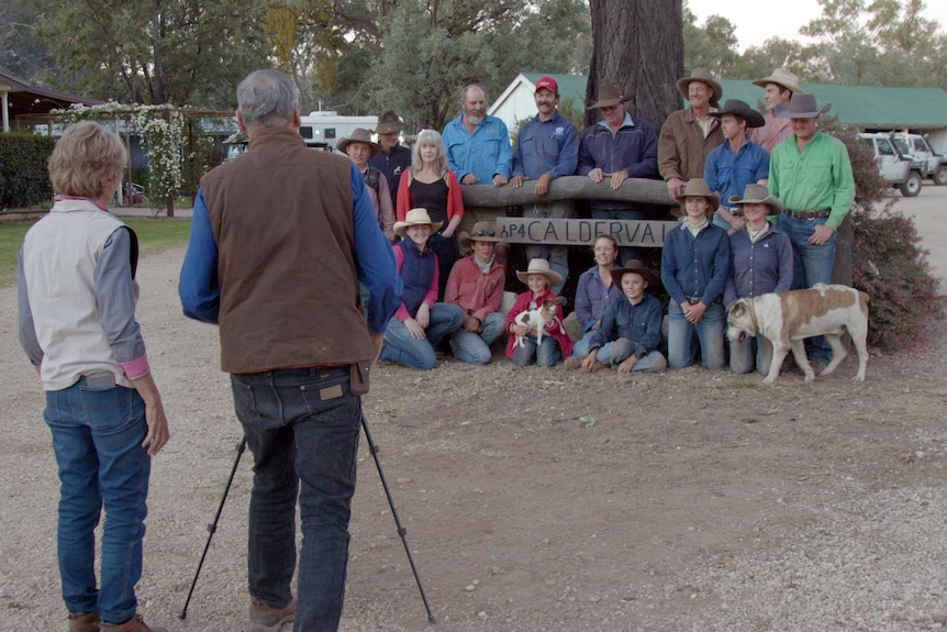 A man and woman taking a photo of a group of people