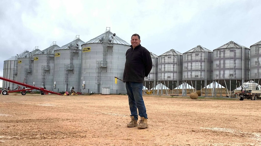 Man stands in front of silos.