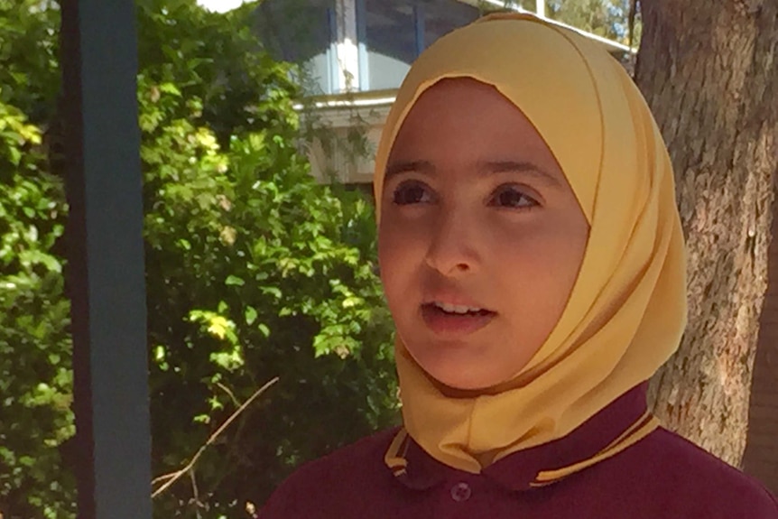 Young refugee Yarah stands in the playground.